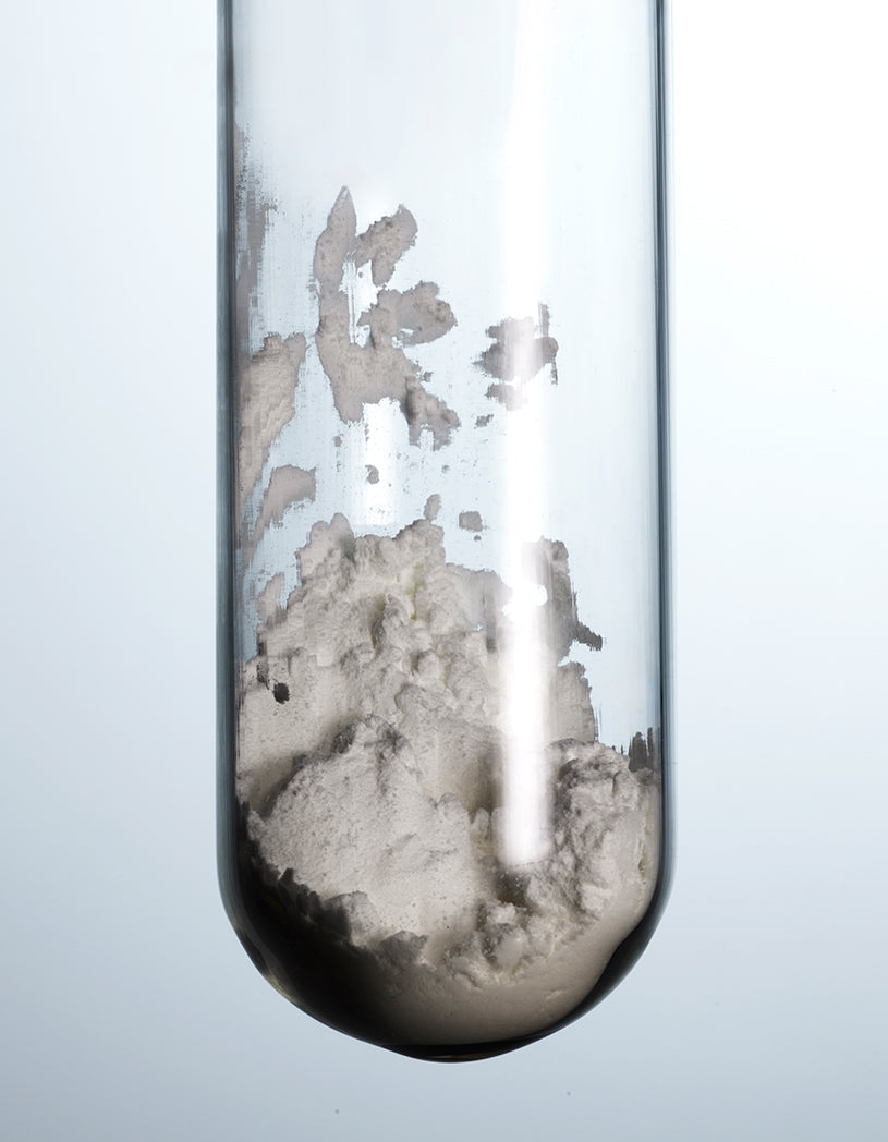 Test tube with white powder against a light gray background